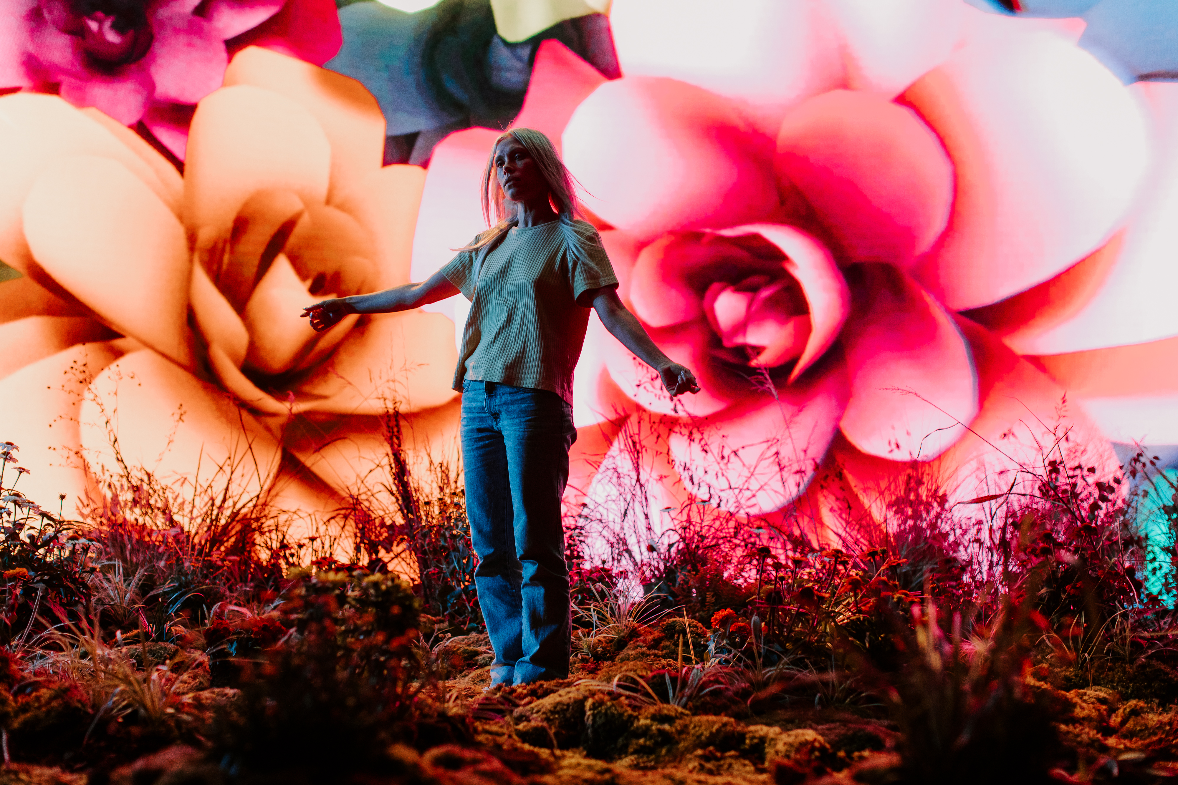 Emily Rowed surrounded by blooming flowers displayed on the LED Volume at Arc Studios.